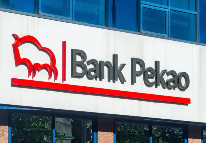Logo Banku Pekao na białej fasadzie budynku, z niebieskimi oknami powyżej.